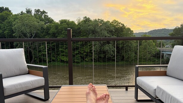 A deck with two sofas and a table, overlooking a river and forested hills. - Riverside Loft with Huge Deck on GAP Trail (Confluence)