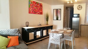 Un espace de vie compact comprenant un coin repas, une kitchenette et un canapé avec des coussins.