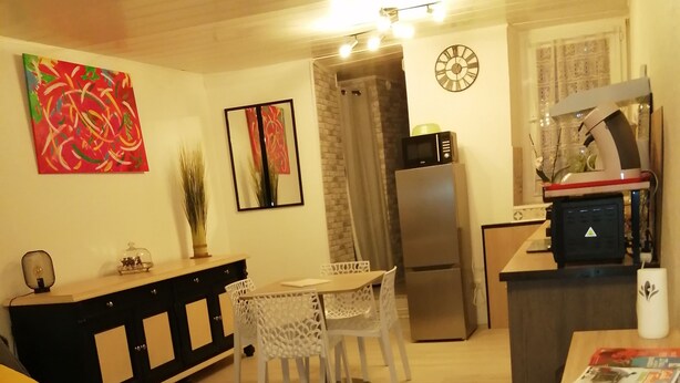 Un espace de vie compact comprenant un coin repas, une cuisine équipée d’un réfrigérateur et d’un four à micro-ondes, ainsi qu’un petit coin salon avec un canapé et une table basse.