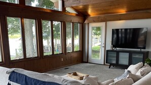 Ein geräumiges Wohnzimmer mit einer großen Eckcouch, einer Holzbalkendecke und einem Fernseher auf einem Schrank.
