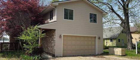 A two-story house with a garage, stone foundation, and a brick driveway.