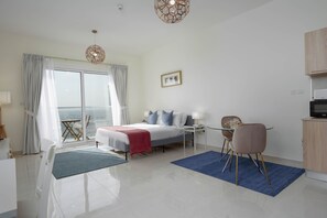 A modern hotel room with a bed, a dining table with chairs, a TV, and a view of the sea through large windows. - Lux BnB I AG Tower I Canal Views (Dubai)