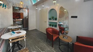 Un interior moderno con una zona de bar, asientos con mesas y sillas, e iluminación decorativa.