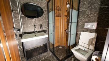 Un baño moderno con cabina de ducha de vidrio, lavabo con espejo y retrete.