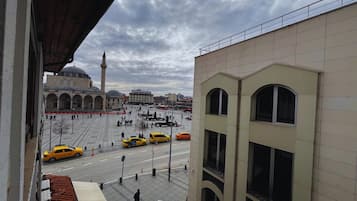 A view of a city square with a mosque, taxis, and a modern building.