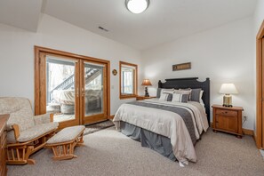 A bedroom with a bed, a chair, a nightstand, and a sliding glass door leading to a balcony.