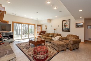 A spacious living room with a large window, a fireplace, a sofa set, and a coffee table.