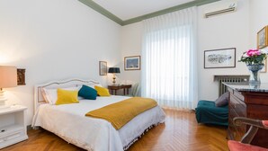A hotel room with a bed, a desk, a chair, a radiator, and a window with curtains. - Elegante e raffinato in zona Crocetta by Wonderful Italy (Torino)