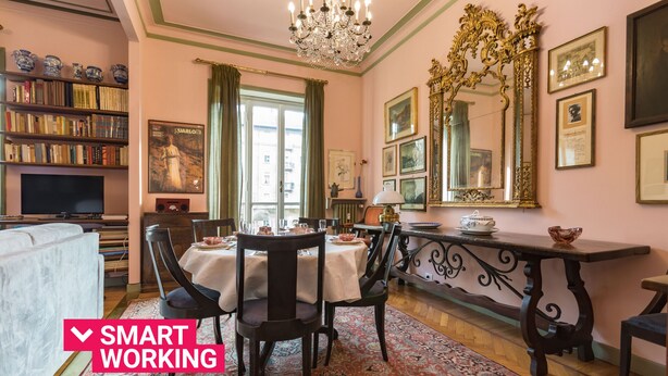A room with a dining table, chairs, a chandelier, a bookshelf, and a television. - Elegante e raffinato in zona Crocetta by Wonderful Italy (Torino)