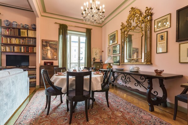 A dining area with a chandelier, a table set for four, and a large ornate mirror. - Elegante e raffinato in zona Crocetta by Wonderful Italy (Torino)