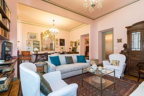 A well-lit living room with a sofa, armchairs, a coffee table, and a bookshelf. - Elegante e raffinato in zona Crocetta by Wonderful Italy (Torino)