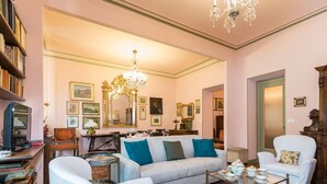 A spacious living room with a sofa, armchairs, a coffee table, and a bookshelf.