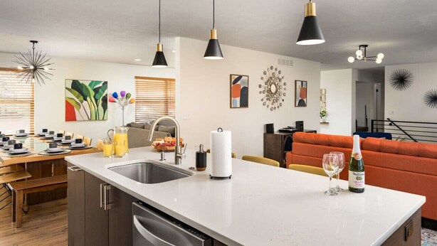 Une cuisine moderne dotée d’un îlot central, de luminaires suspendus et d’un coin repas avec une table mise pour le repas.
