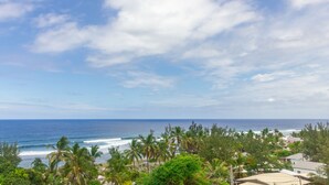 Vista costera con palmeras, olas del océano y cielo despejado.
