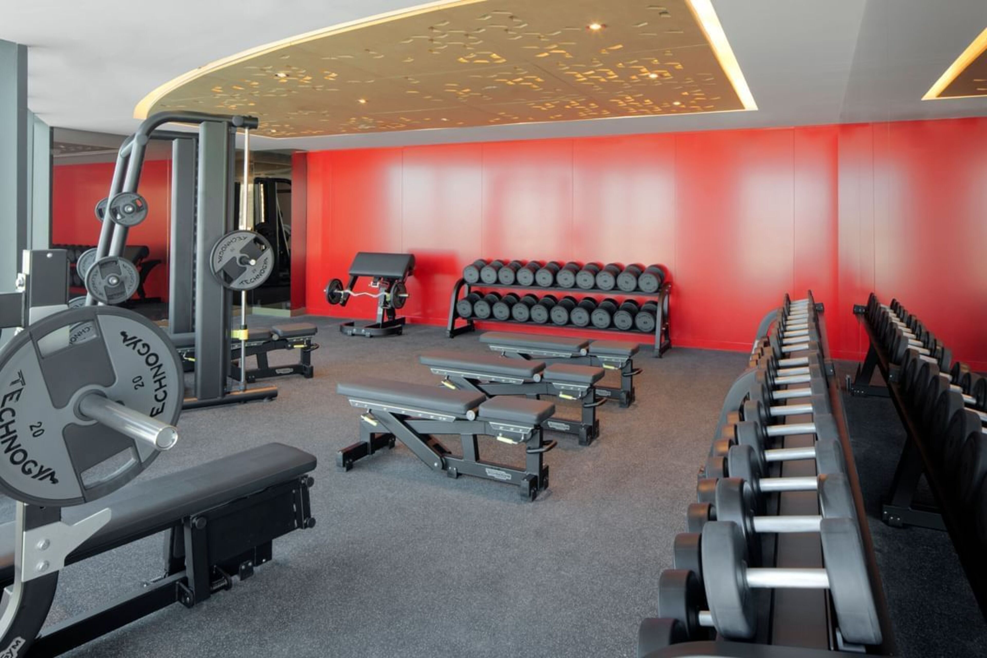 Ein Fitnessstudio mit Gewichten, Bänken und Kurzhanteln.