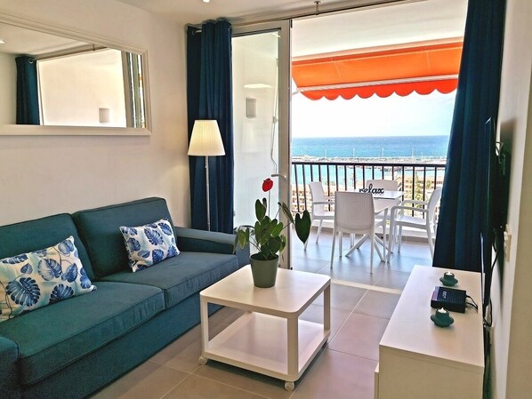 A living room with a sofa, coffee table, and a balcony with a view of the sea. - 5mn from the beach: Achacay Standing apartment with sea and mountain views  (Los Cristianos)