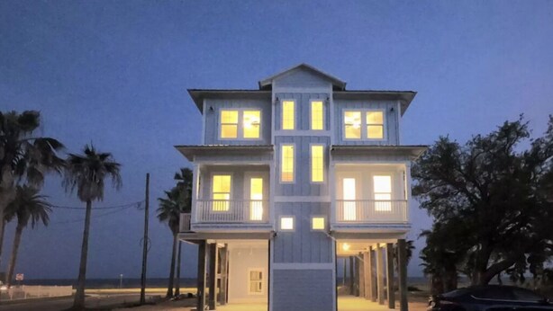 Une maison à deux étages avec un balcon, située près d’une plage.