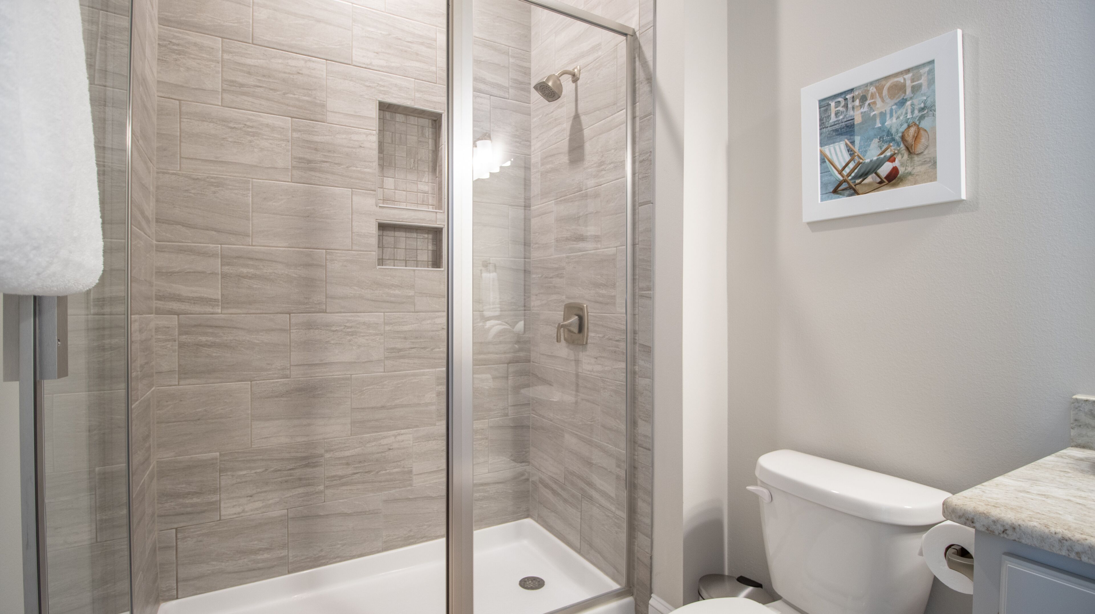 A modern bathroom with a glass-enclosed shower, a toilet, and a sink.