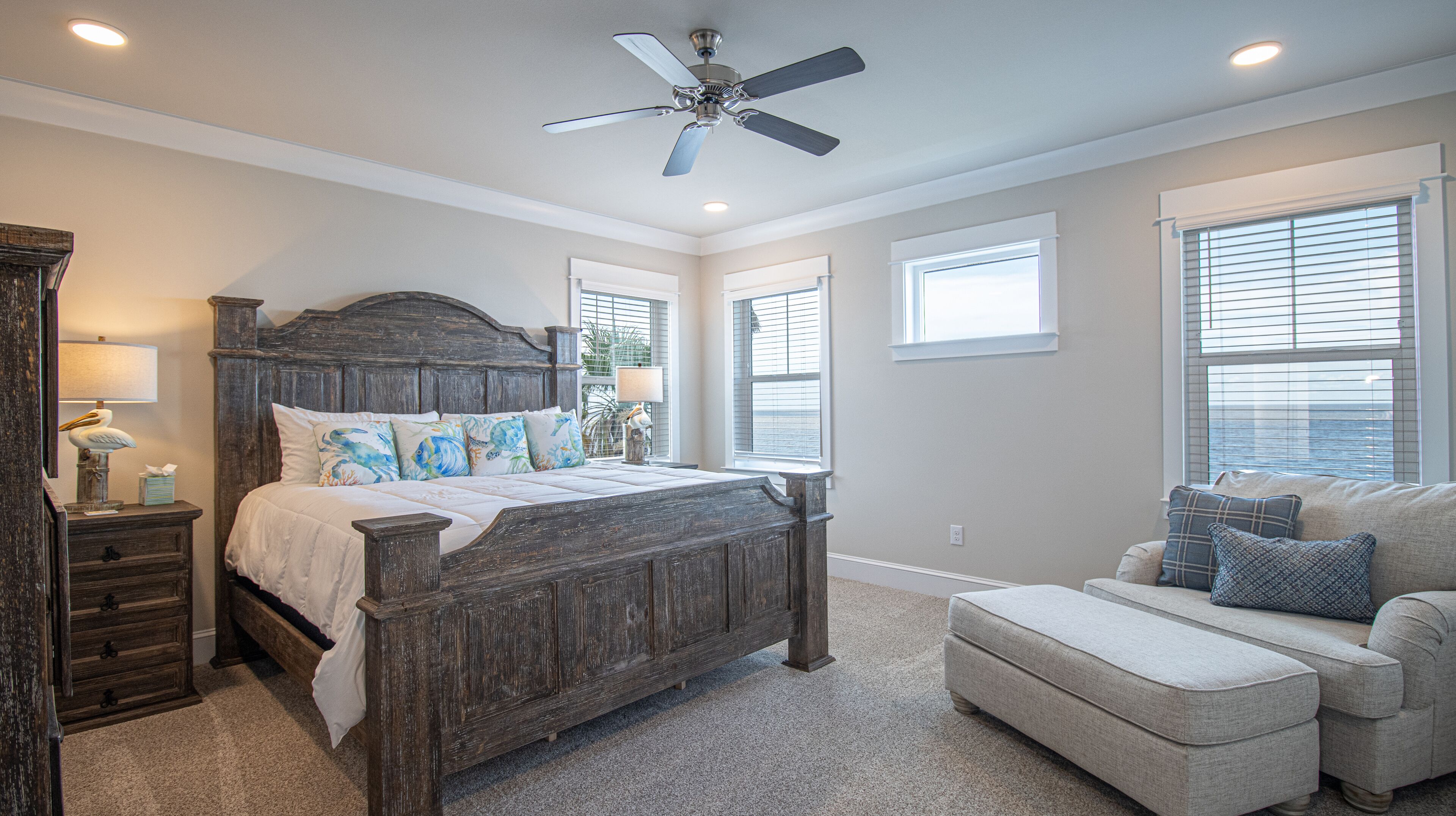 A bedroom with a wooden bed, a nightstand, a dresser, a ceiling fan, and a window with blinds.