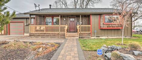 A single-story house with a front porch, a garage, and a small front yard with a paved walkway.