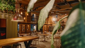 A cozy restaurant with wooden tables and chairs, hanging plants, and a warm ambiance. - One66 Hotel (Ljubljana)