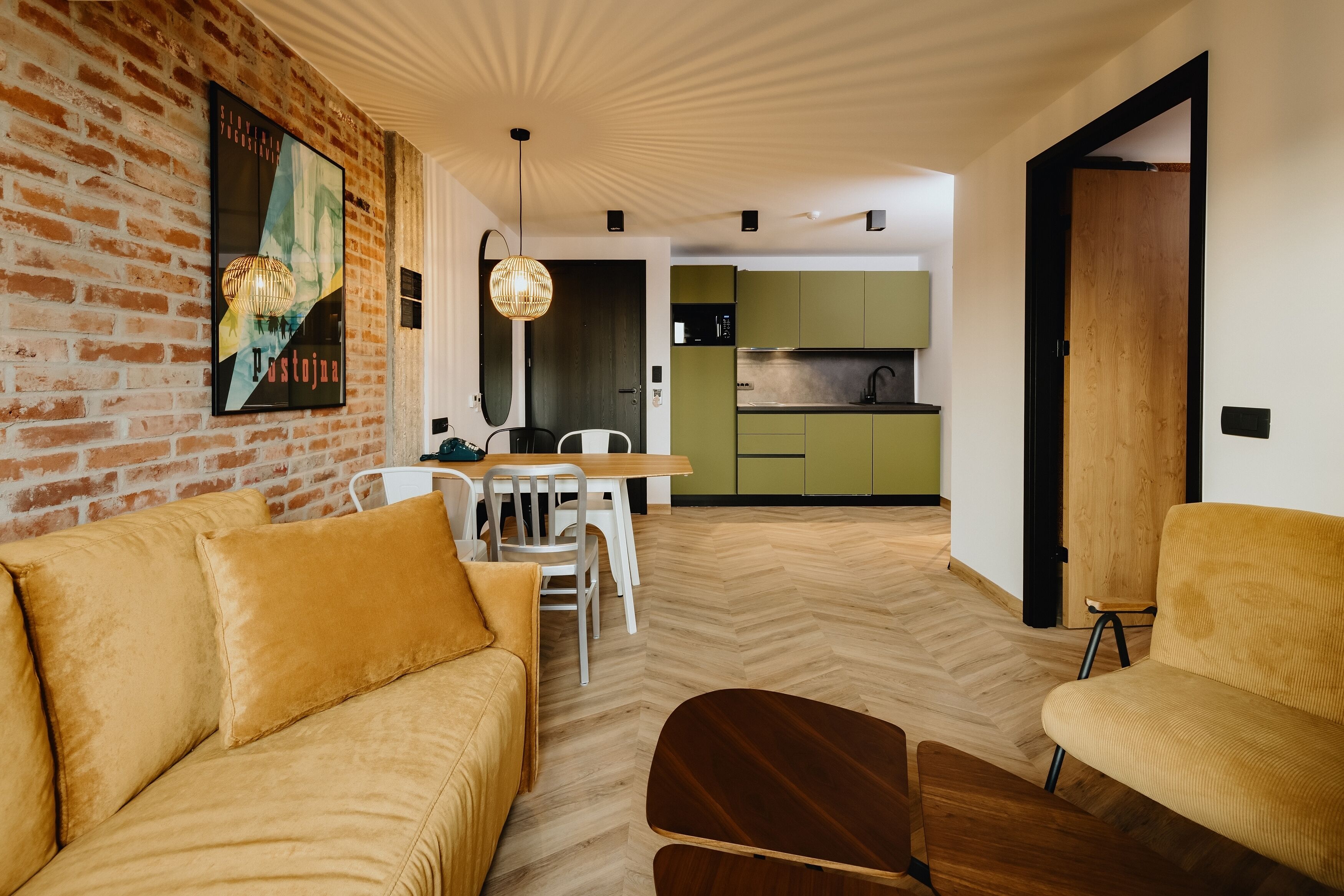 Un salon moderne avec un mur en briques, un plancher en bois et un coin repas comprenant une table et des chaises.
