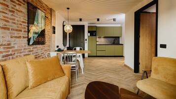Un salon moderne avec un mur en briques, un plancher en bois et un coin repas comprenant une table et des chaises.