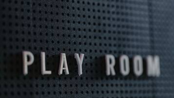 A perforated wall with the words "PLAY ROOM" in white letters.