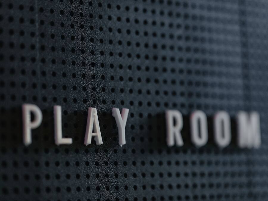 A perforated wall with the words "PLAY ROOM" in white letters.