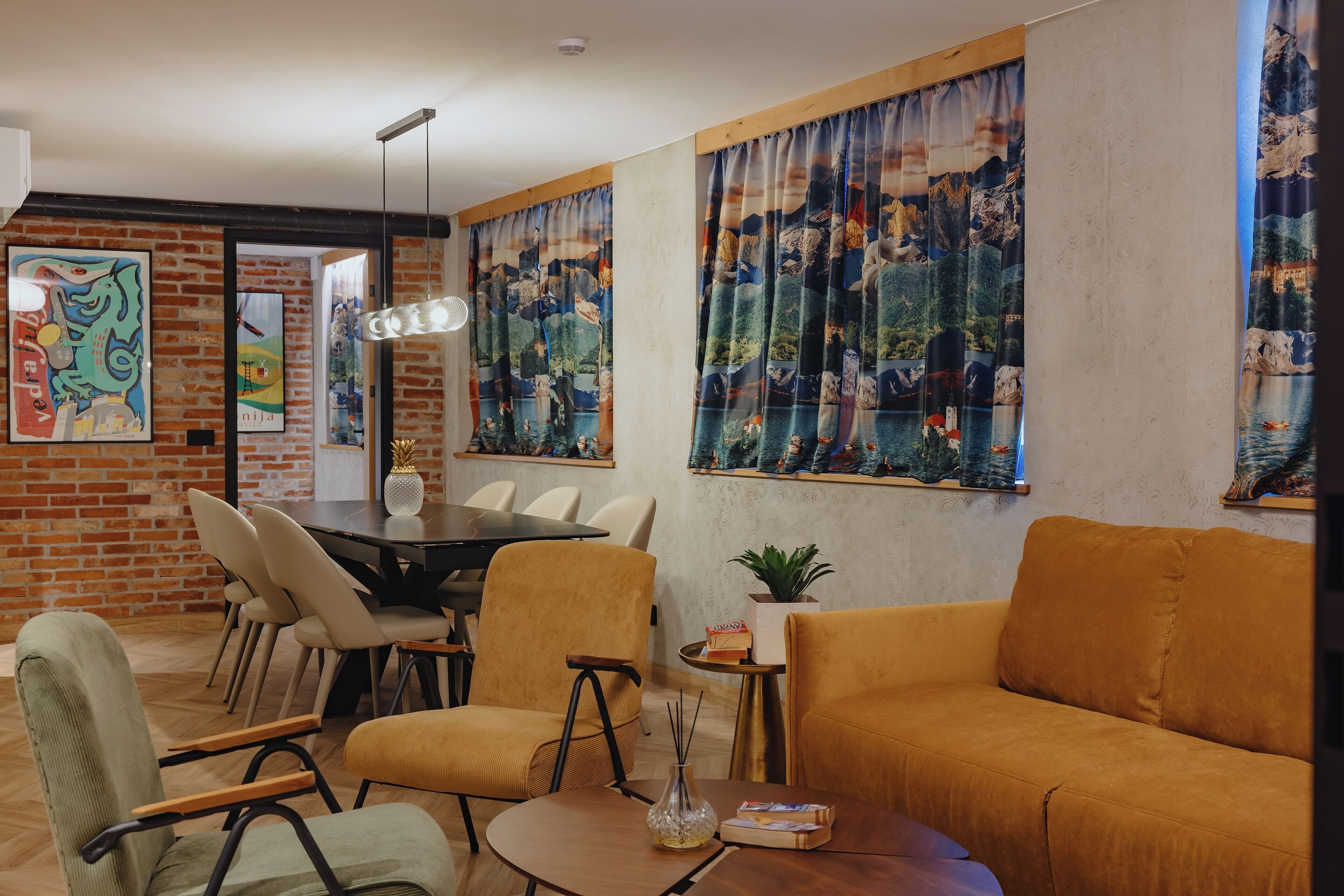 A modern living room with a brick wall, a dining area with a round table and chairs, and large windows with curtains.