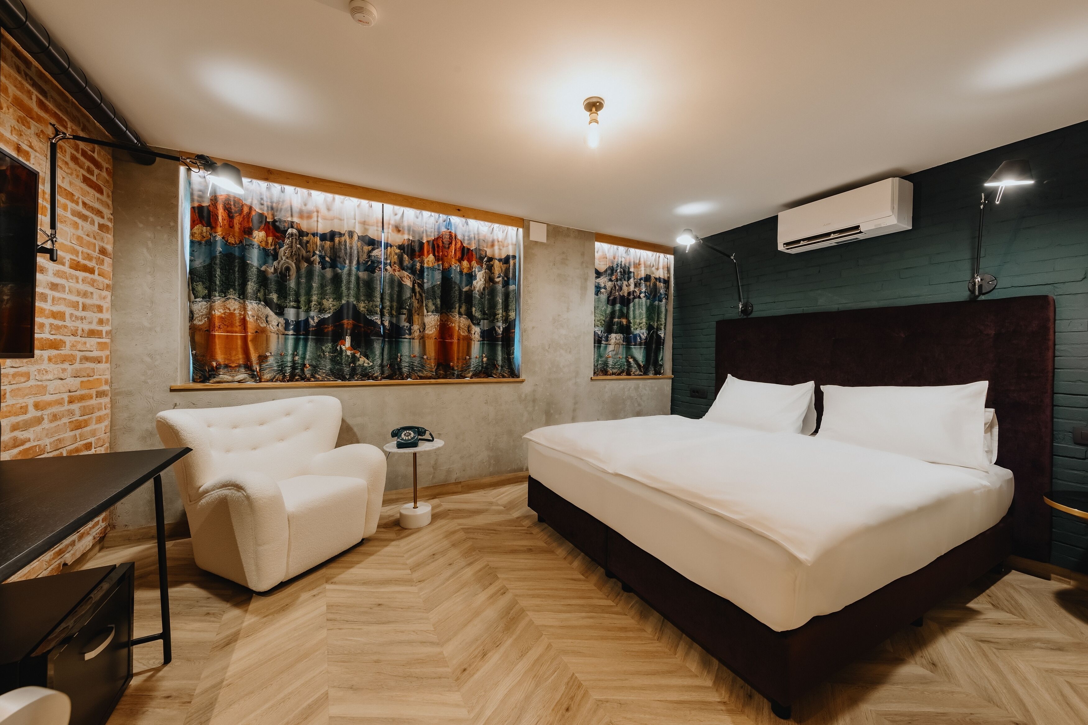 A modern bedroom with a large bed, a desk, a chair, and a window with a curtain.