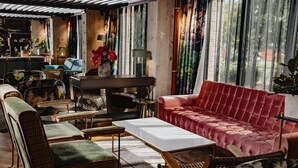 A cozy living room with a red sofa, green armchairs, and a white coffee table. There is a piano and a plant in the corner. - One66 Hotel (Ljubljana)