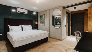 A modern bedroom with a large bed, a round mirror, and a dining table. - One66 Hotel (Ljubljana)