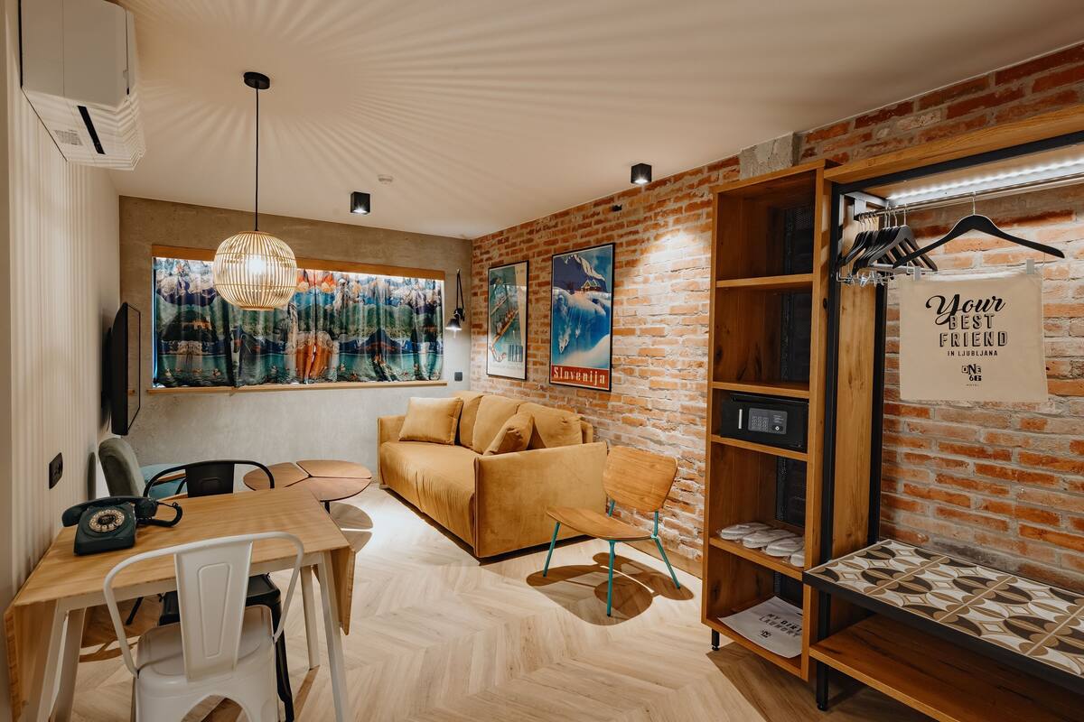 Um quarto aconchegante com parede de tijolos, um sofá, uma mesa de madeira e um lustre.