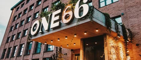 A hotel entrance with a large sign reading "ONE66" and a modern brick facade.