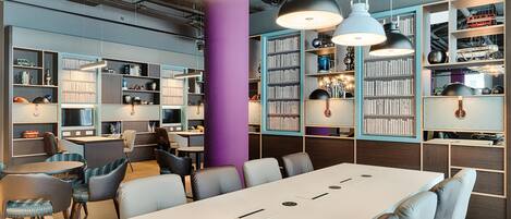 A modern library with bookshelves, a large table, and comfortable seating.