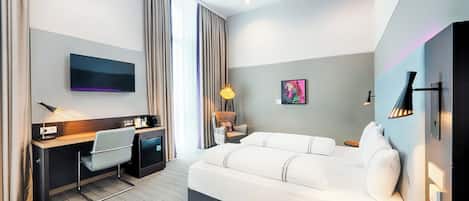Una habitación de hotel moderna con cama, escritorio, silla y televisor de pantalla plana.