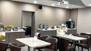 A hotel restaurant with tables and chairs, a counter with coffee machines, and a television. - Jinjiang Inn (Beijing Anzhenli) (Beijing)