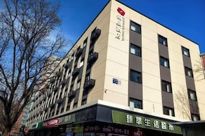 A multi-story building with a flat facade, multiple balconies, and a sign indicating it is a residential complex.