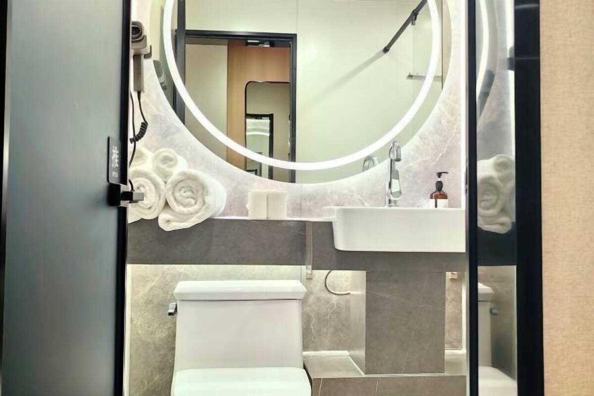 A modern bathroom with a toilet, sink, and mirror.