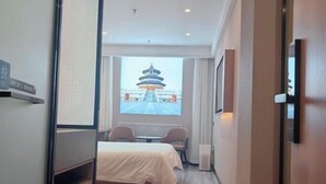 A hotel room with a bed, a desk, and a view of a traditional pagoda through a window. - Jinjiang Inn (Beijing Anzhenli) (Beijing)