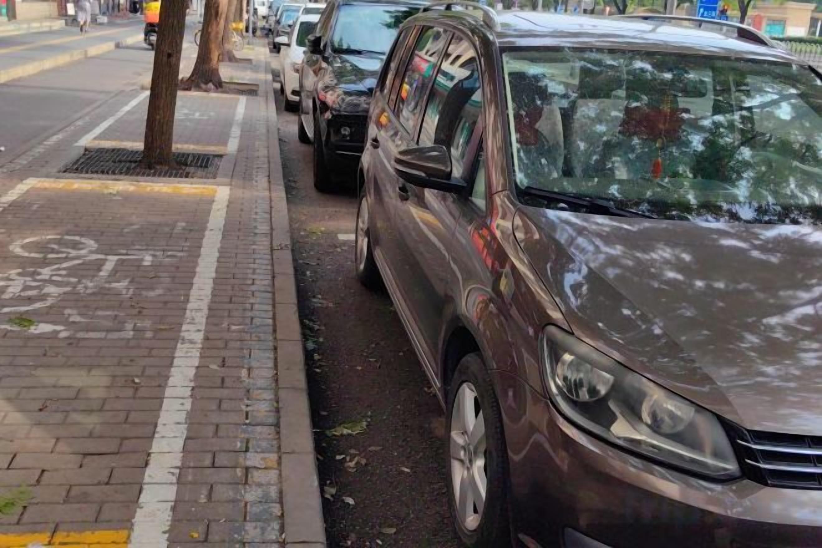 Un coche estacionado en una calle urbana con un carril bici en la acera.