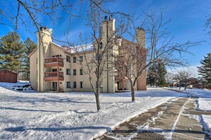 Un edificio de varios pisos con balcón, suelo cubierto de nieve y cielo despejado.