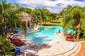 A pool area with lounge chairs, a thatched-roof structure, and palm trees. - 5-star villa for rent in Moroccan-style (La Romana)