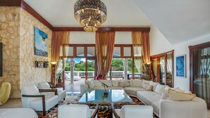 A spacious living room with a large sectional sofa, a glass coffee table, and a stone wall. - 5-star villa for rent in Moroccan-style (La Romana)