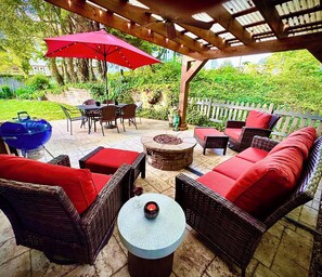 Relax in a serene outdoor space with a pergola, fire pit, and wicker furniture.