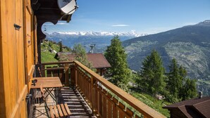 A wooden balcony with a view of snow-capped mountains and a ski lift in the background. - This stunning, bright and comfortable chalet can accommodate up to 8 people. Located on the Chemin d (Les Masses)