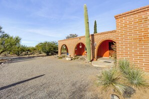 A building with brick walls and arched doorways, surrounded by cacti and desert vegetation. - Private Pool & Fire Pit! Walkable Tucson Retreat (Tucson)