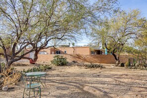 A desert landscape with a brick building, cacti, and a metal table and chair. - Private Pool & Fire Pit! Walkable Tucson Retreat (Tucson)