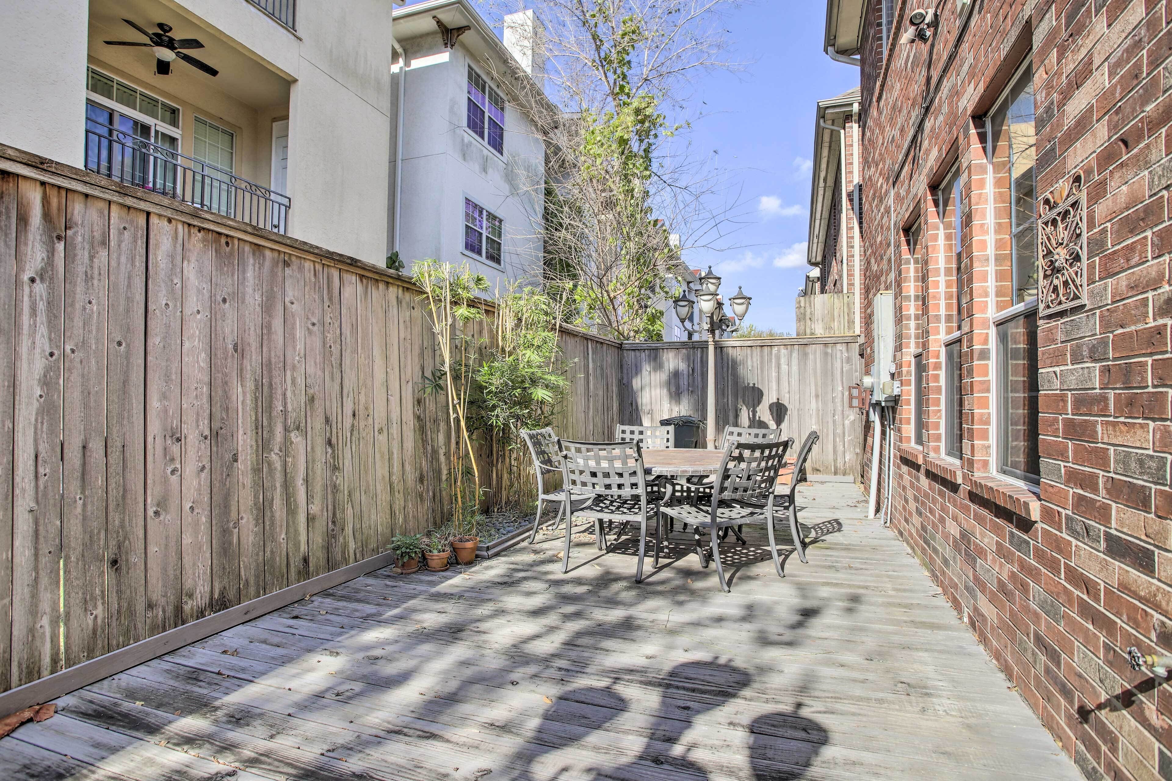 A patio with a wooden deck, a table and chairs, and a brick wall.